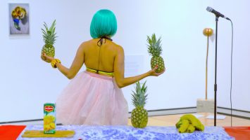 Priya Mistry holds two pineapples in front of a colourful table