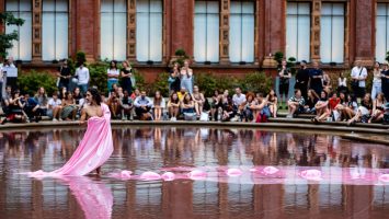 A male dancer stands in a fountain at the V&A, trailing long pink fabric through the water