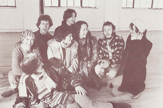 Sepia film photo of eight young dancers sat in the CDS performance studio